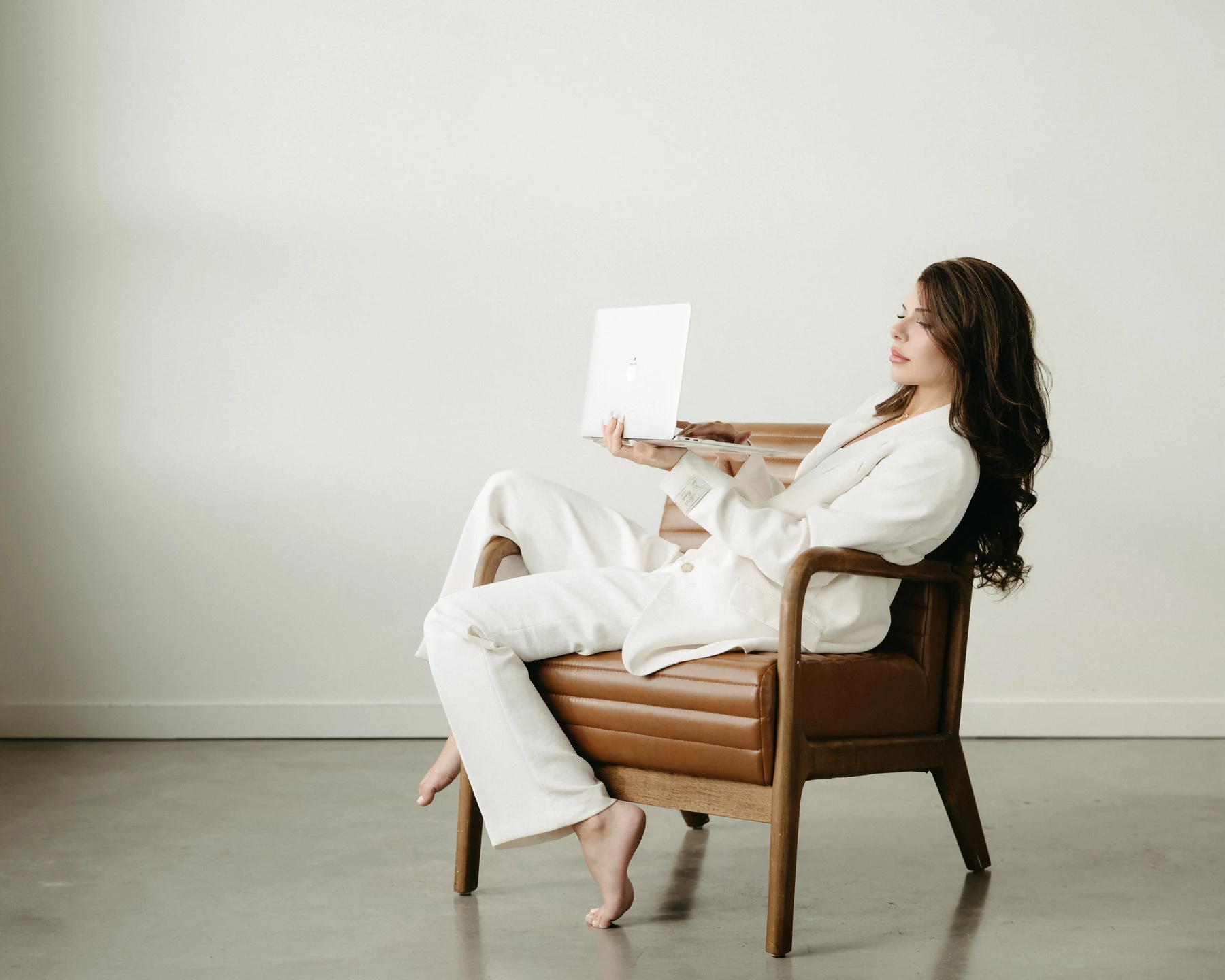 Ashley seated with laptop in an editorial studio setting
